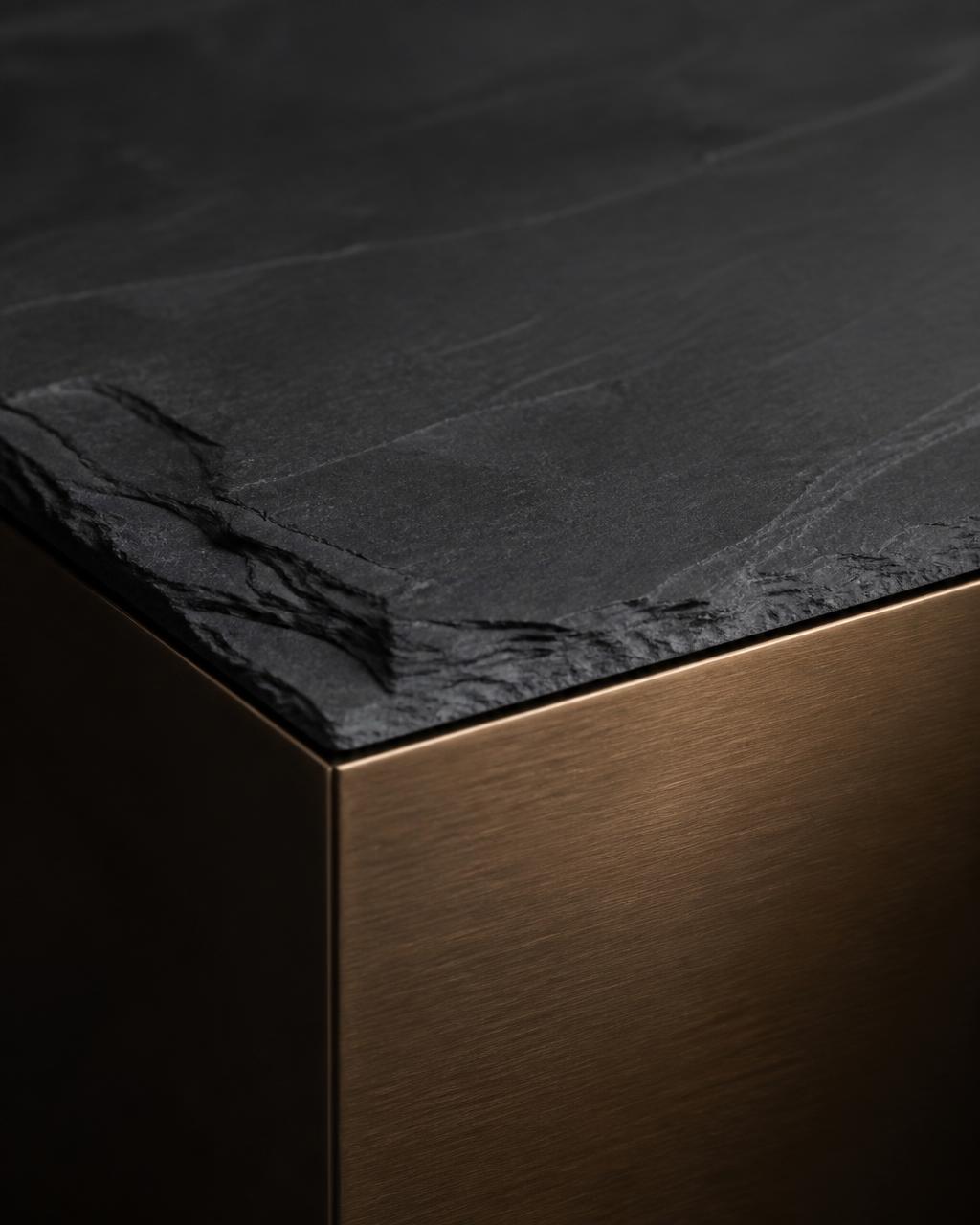 Detail of dark stone and brushed metal surfaces meeting at a precise edge